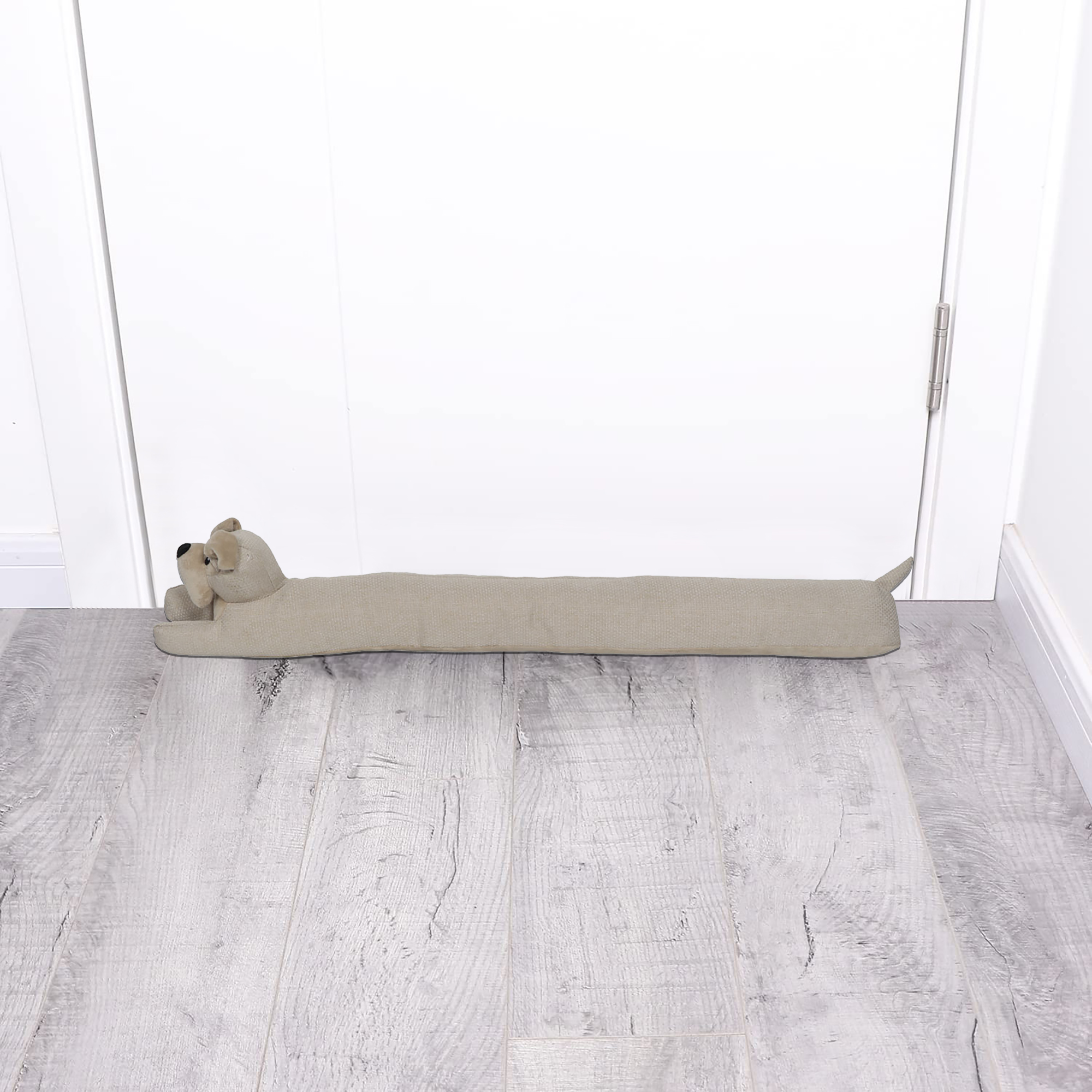 Dog draft stopper placed at the bottom of a closed white door on a gray wood floor