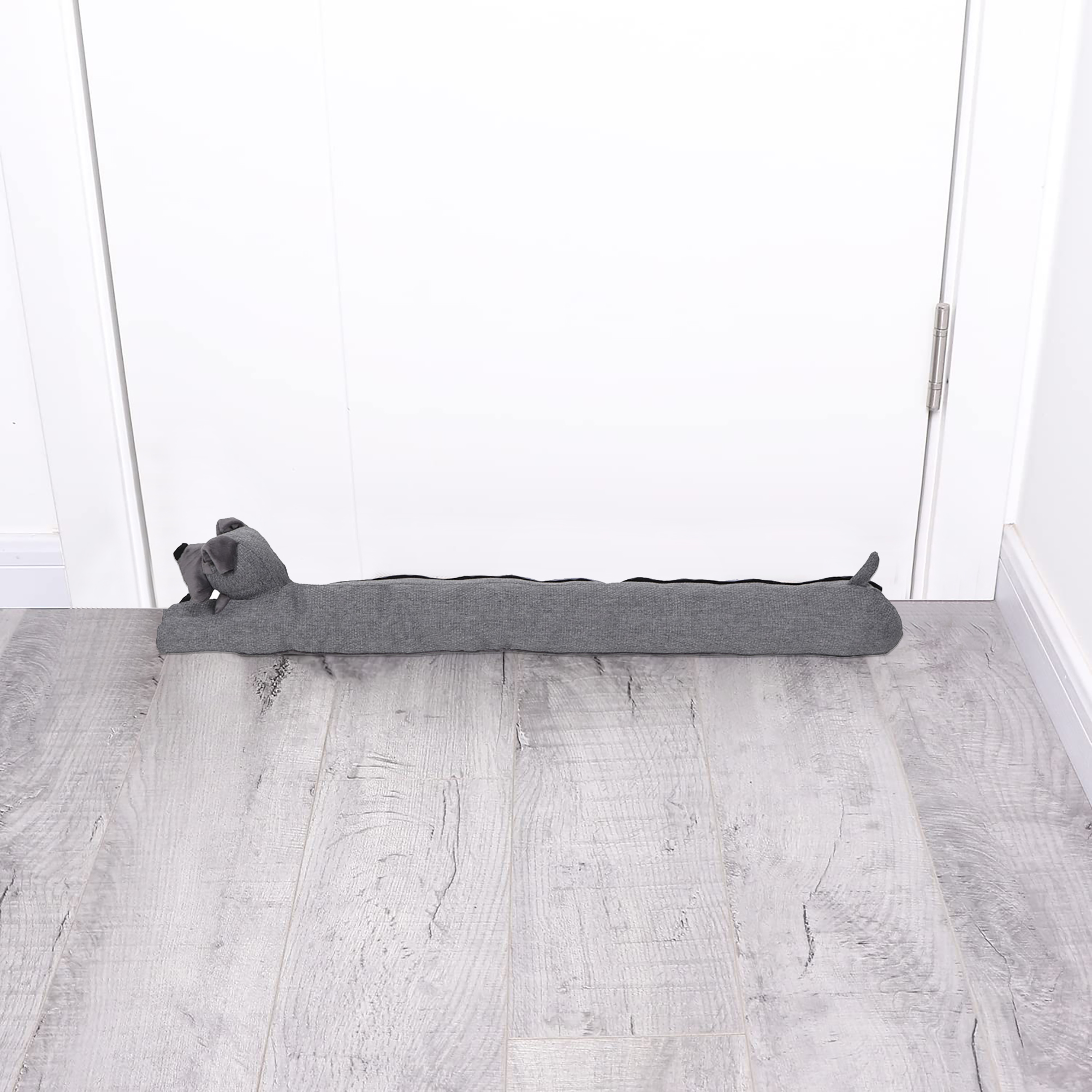 Dog draft stopper placed at the bottom of a closed white door on a gray wood floor