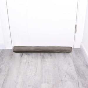Corduroy draft stopper placed at the bottom of a closed white door on gray wood floor