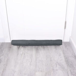 Corduroy draft stopper placed at the bottom of a closed white door on gray wood floor