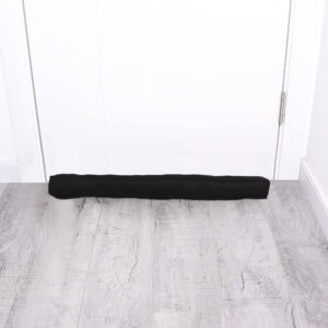 Corduroy draft stopper placed at the bottom of a closed white door on gray wood floor