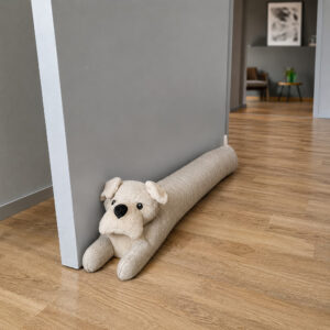 Beige dog draft stopper lying against the base of a gray interior door in a modern hallway.