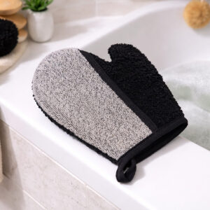 Dual-texture exfoliating glove with gray and black sides on bathtub edge