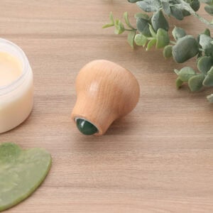 Wooden jade stone face roller placed on table with skincare items