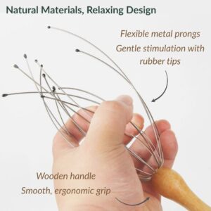 Close-up of hand holding head massager showing flexible metal prongs with rubber tips for gentle stimulation and smooth wooden handle for ergonomic grip
