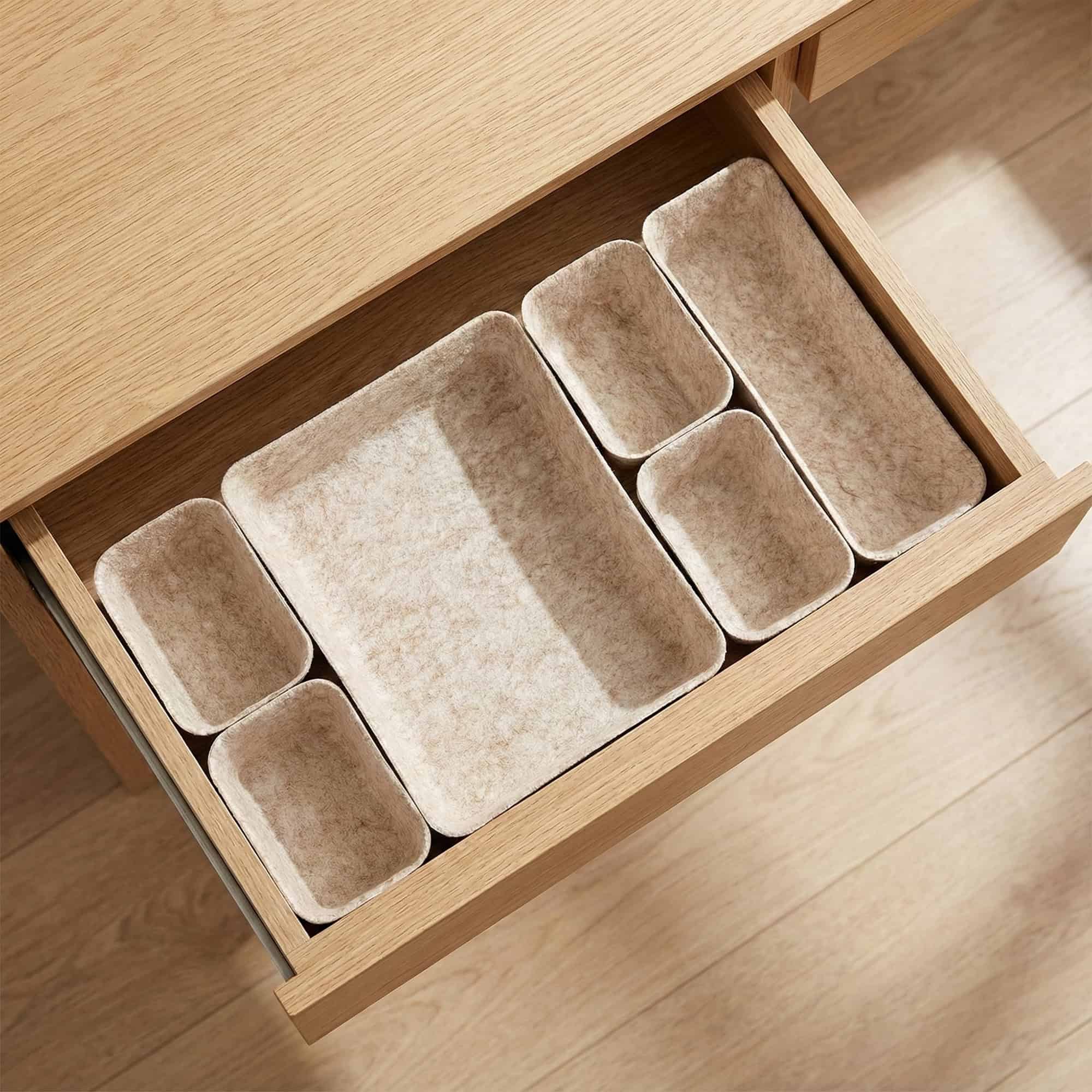 Seven-piece beige felt drawer organizer bins arranged in an open wooden drawer, shown empty.