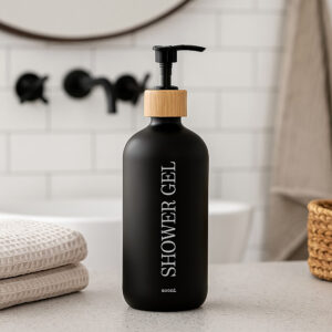 Black shower gel bottle on bathroom counter with towels and basket