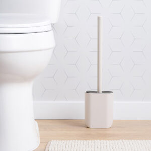 Beige toilet brush holder placed beside toilet