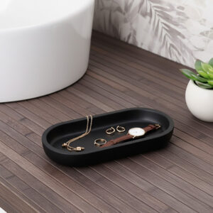 Black oval tray holding jewelry on bathroom counter