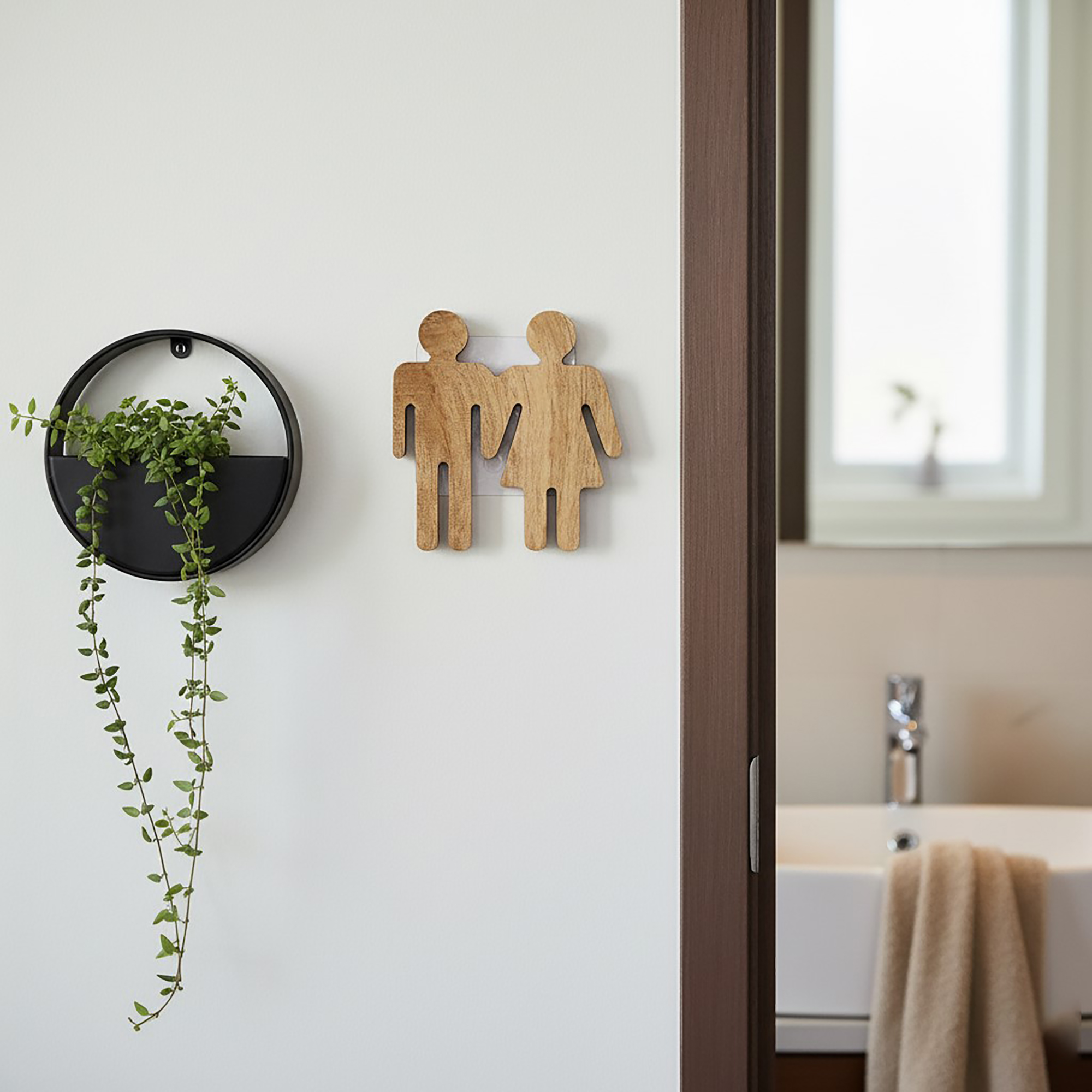 Natural wooden restroom sign installed on door with bathroom visible in background