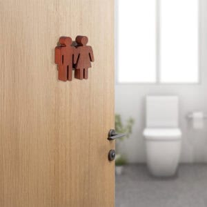 Natural wood unisex restroom sign mounted on wooden door in modern bathroom