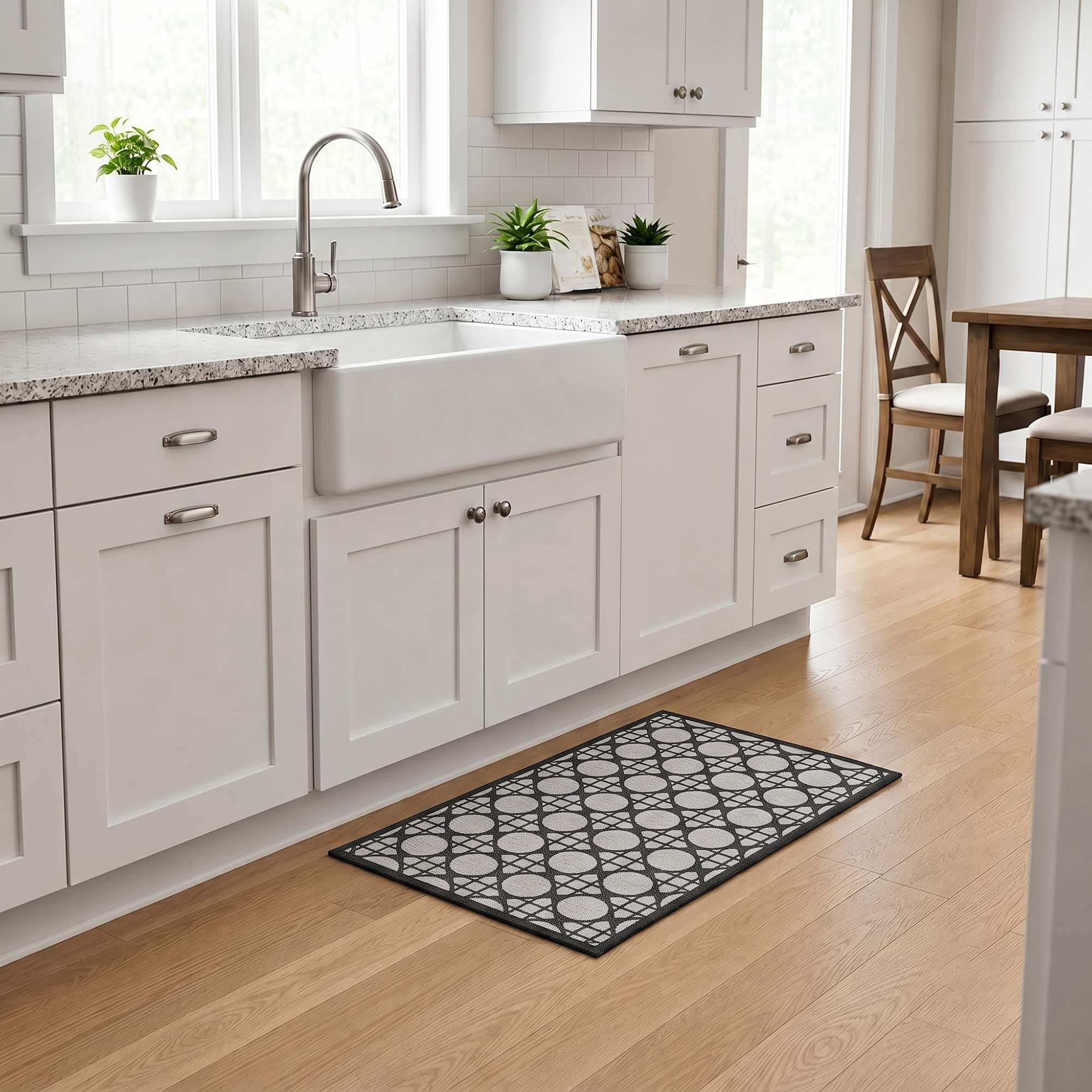 2- Cream and charcoal cane pattern kitchen rug in front of a white farmhouse sink on light wood flooring