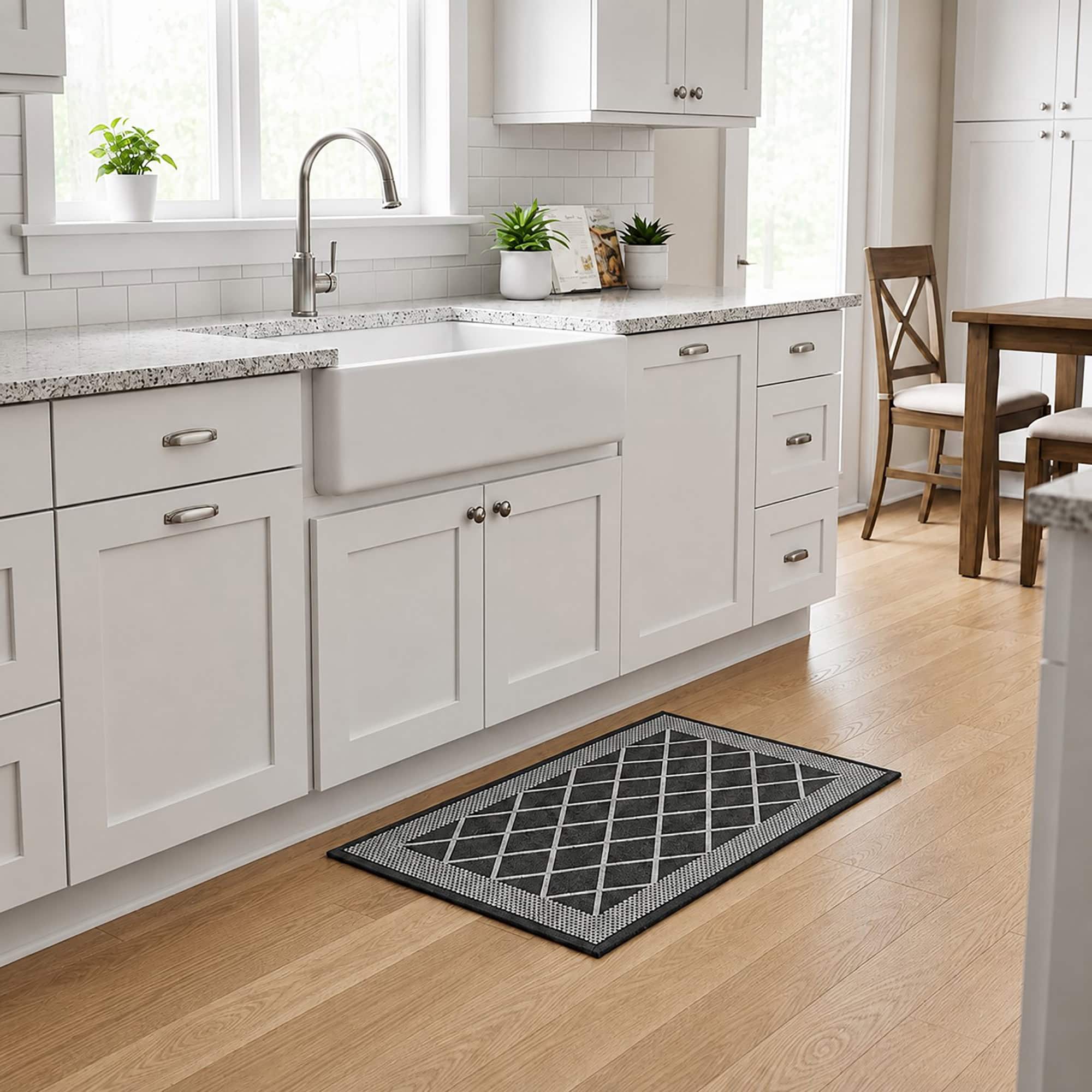 2- Charcoal gray diamond trellis kitchen rug in front of a white farmhouse sink on light wood flooring