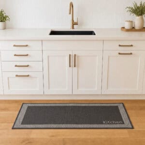 2- Charcoal and cream bordered kitchen runner with Kitchen word on wood floor in front of a white sink