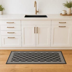 2- Charcoal gray diamond trellis kitchen runner with cream border on wood floor in front of a white sink