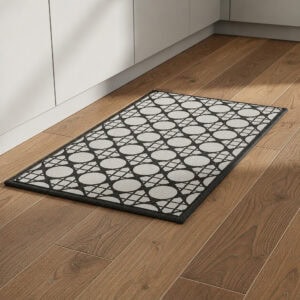 9- Cream and charcoal cane medallion kitchen rug on wood floor beside white kitchen cabinets