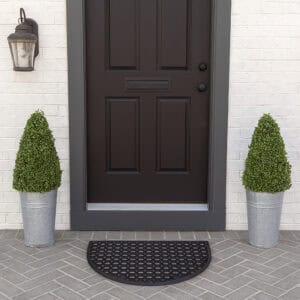 Black half-moon rubber doormat at front door with potted plants