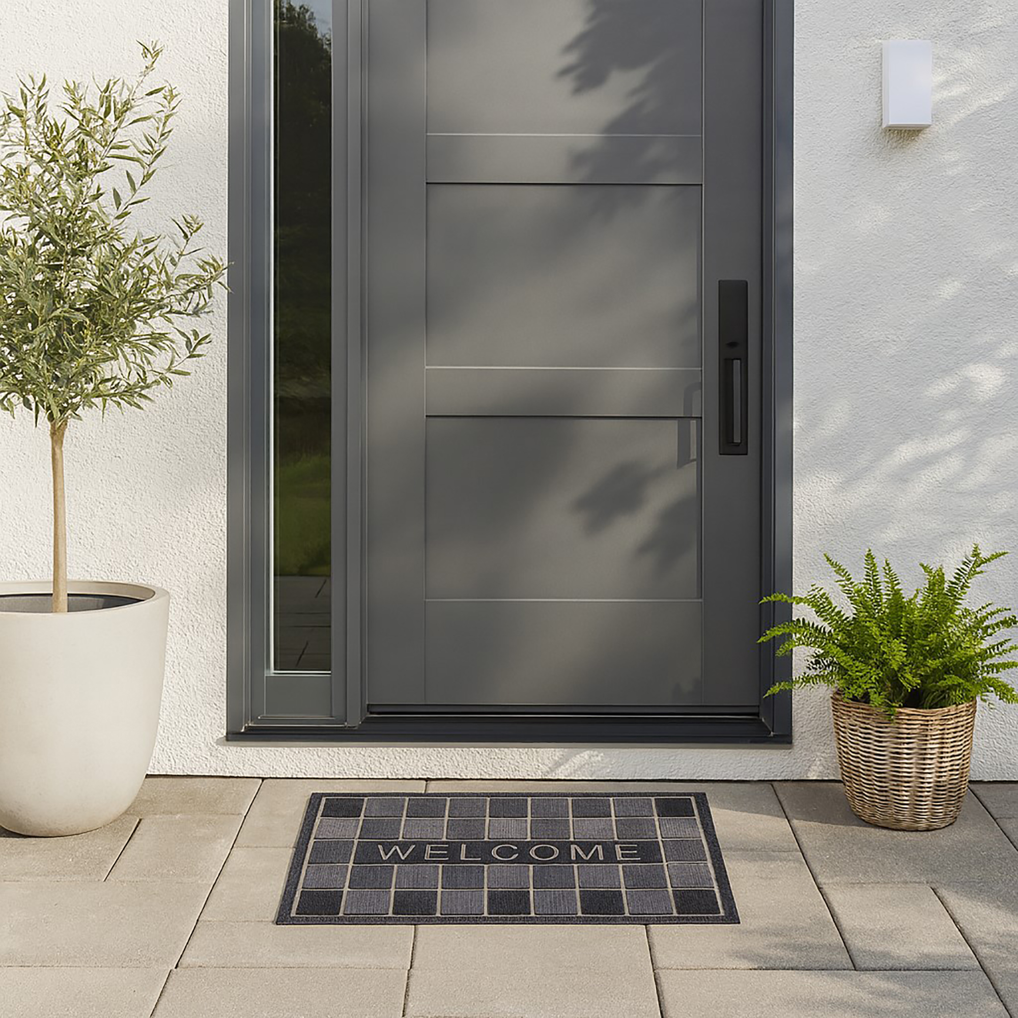 Welcome mat in front of modern gray entrance door outdoor scene