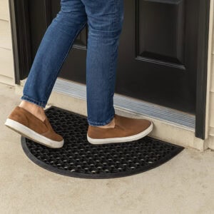 Person stepping on black rubber half-moon doormat at entryway