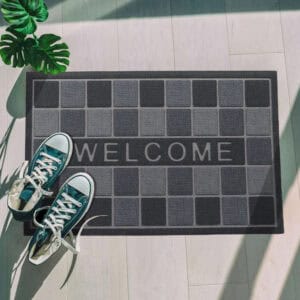 Top view gray welcome mat with sneakers by entryway