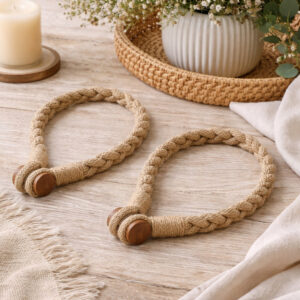 Braided jute curtain tiebacks with a wooden button closure, laid on a linen cloth over a wooden tray.