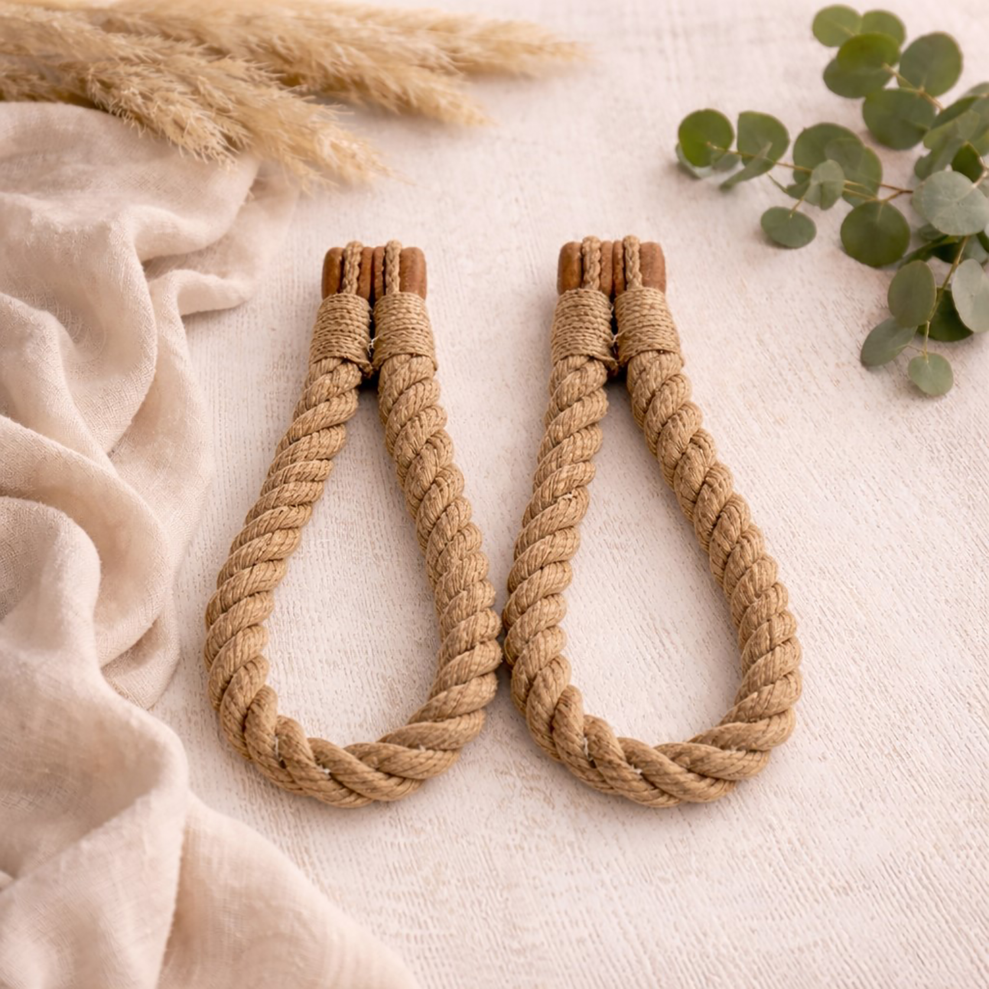 Natural jute twisted rope curtain tiebacks with wooden magnetic ends, laid flat on a white surface