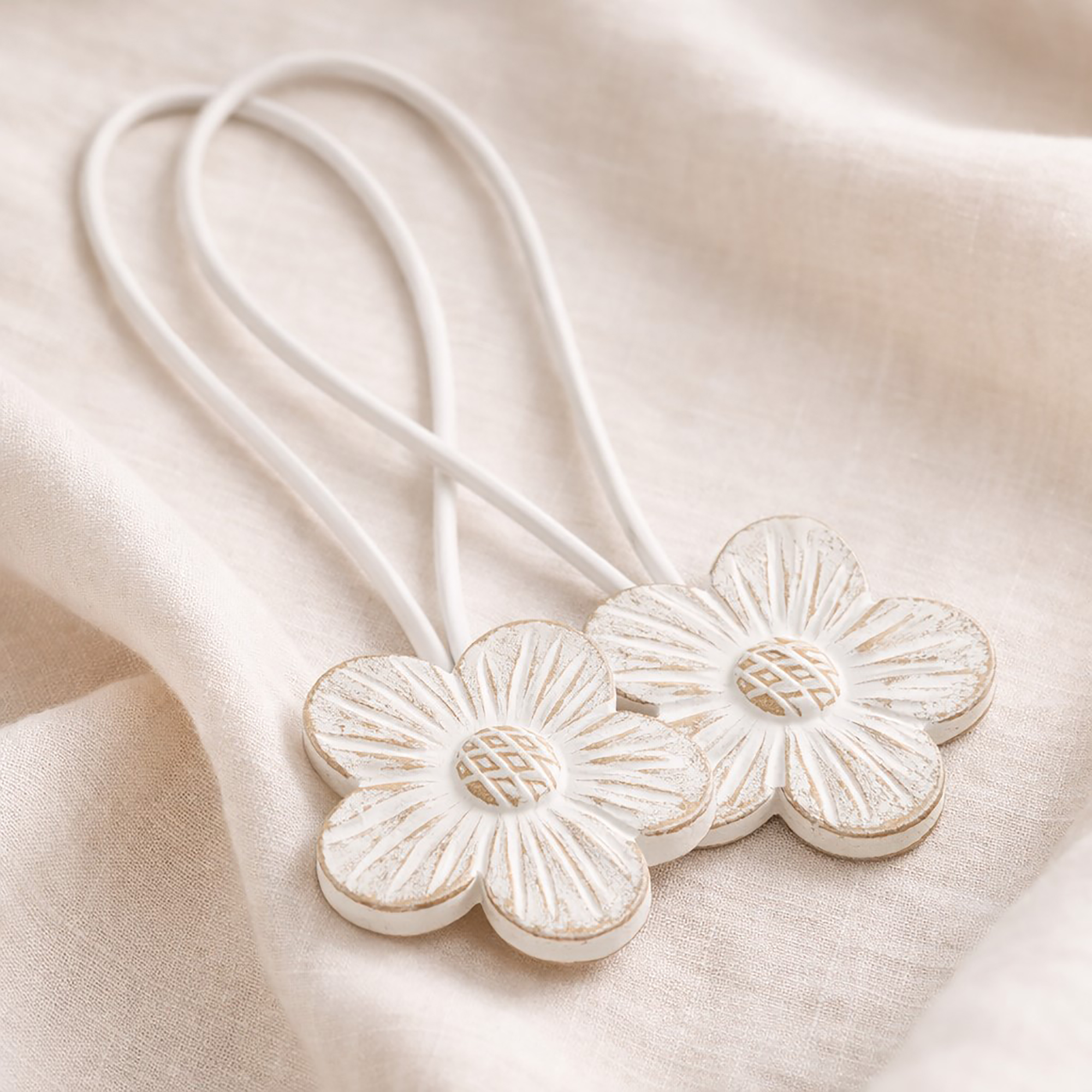 White carved resin flower curtain tiebacks with white cord on linen fabric