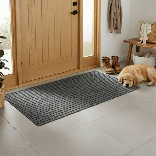 Gray ribbed entryway doormat at front door with sleeping golden retriever, boots, and wooden bench in entryway