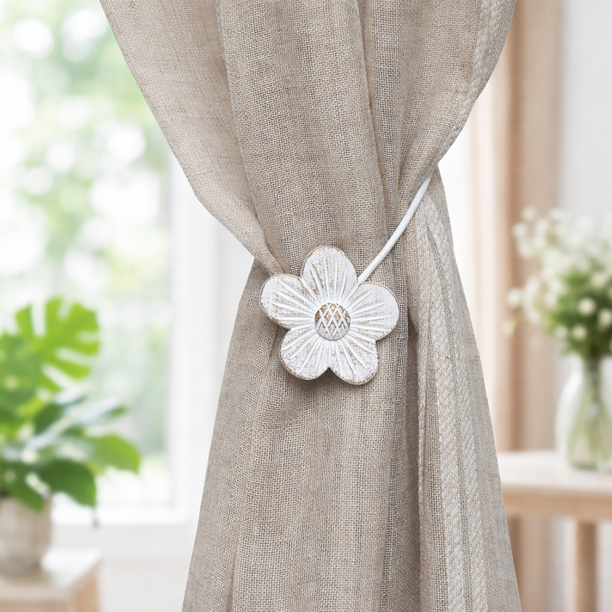 White resin flower tieback on textured linen curtain interior