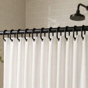 Dark rings holding fabric panel in tiled shower space with soft lighting