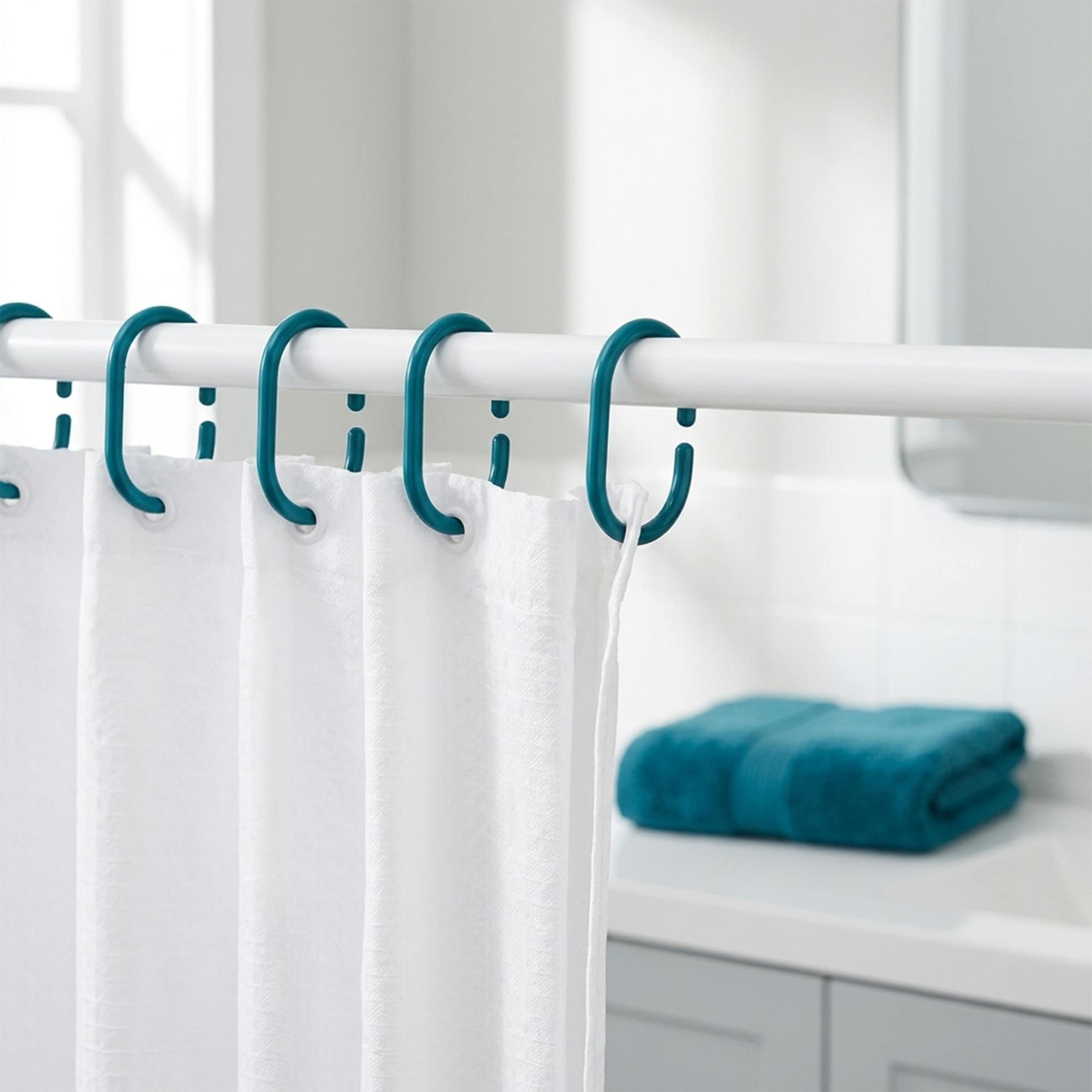 Teal plastic shower curtain hooks installed on white rod holding curtain in bright modern bathroom setting