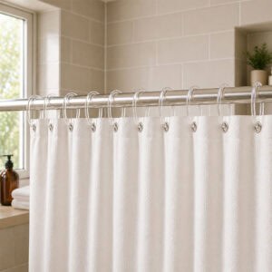 Clear shower curtain rings holding white curtain in bright bathroom with tiled wall and window light
