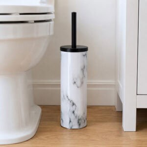 White marble toilet brush holder with black handle standing on wood flooring between a white toilet and a cabinet in a bright bathroom.