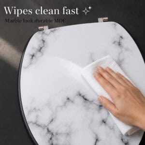 Hand wiping a white marble look toilet seat with a cloth, showing the durable MDF surface that wipes clean fast and keeps its glossy finish.