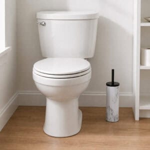 Slim marble look toilet brush holder placed beside a white toilet in a clean neutral bathroom, compact stand that tucks into a narrow corner.