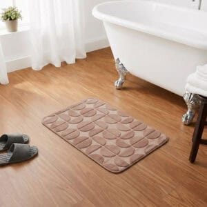 Caramel rectangular bath mat placed in front of a clawfoot bathtub on warm honey wood flooring, classic chic bathroom setting, soft plush texture inviting comfort