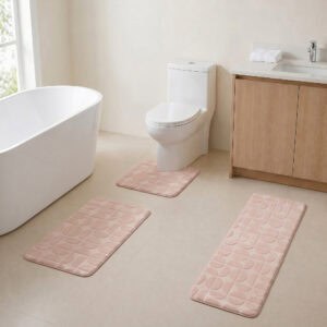 Blush pink 3-piece bath rug set displayed in a modern bathroom with freestanding tub, toilet and wood vanity.