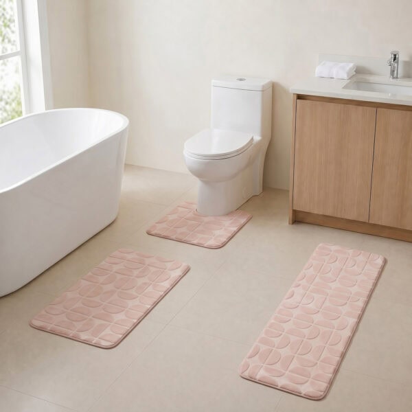 Blush pink 3-piece bath rug set displayed in a modern bathroom with freestanding tub, toilet and wood vanity.