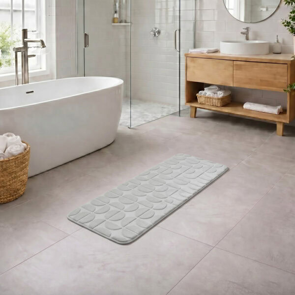 Light gray long bathroom runner placed between bathtub and vanity in a modern bathroom with light tile floor and natural daylight, soft plush comfort along the entire length