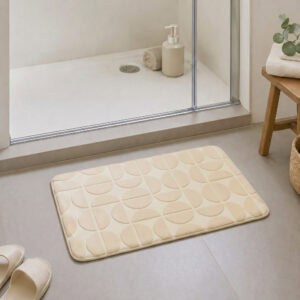 Cream plush bath mat at the exit of a walk-in glass shower, modern Scandinavian bathroom with light tile floor and natural daylight, soft landing after every shower