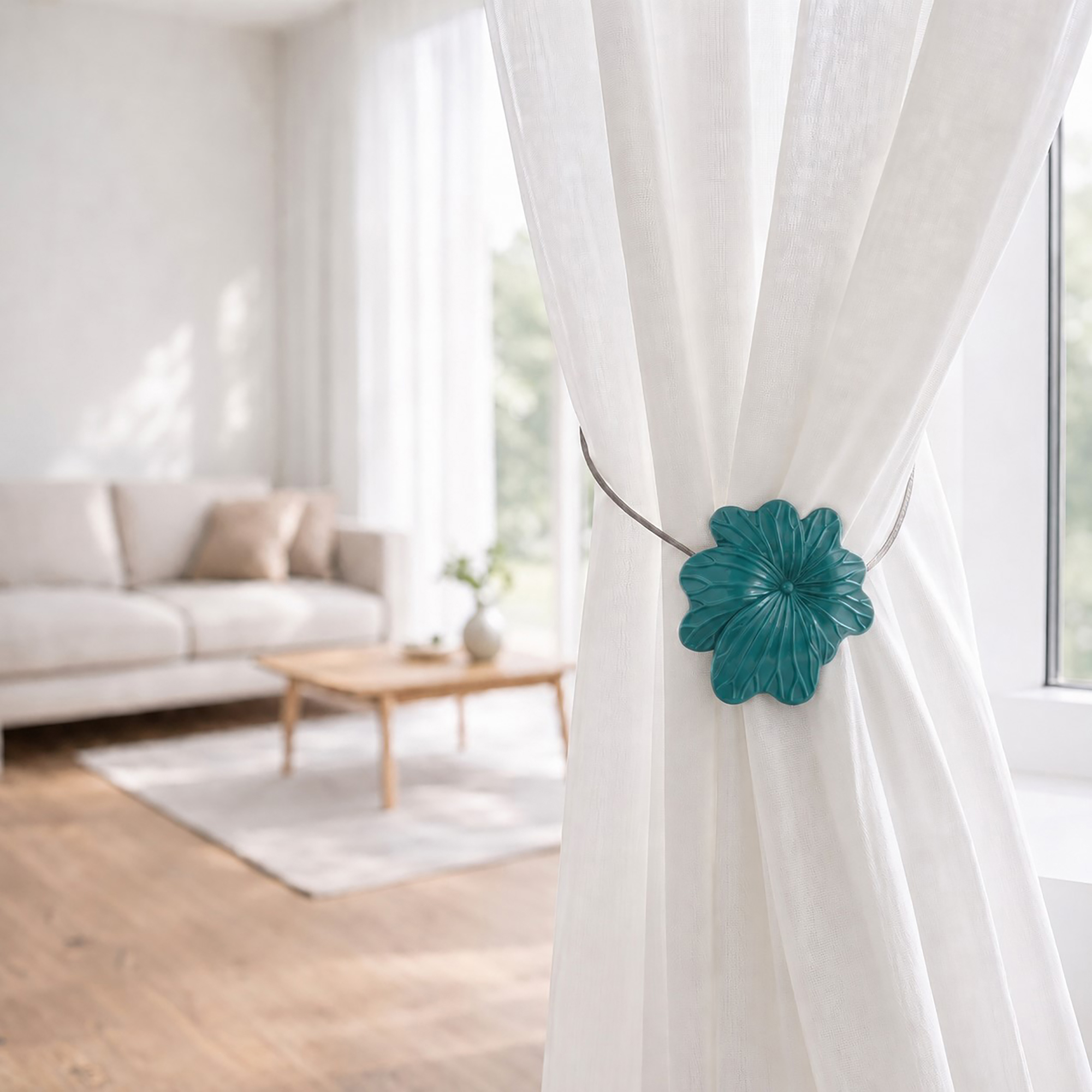 08 (living room lifestyle): Sheer white curtain held back by the dark green flower tieback in a bright living room with a neutral sofa and wood coffee table softly blurred behind.
