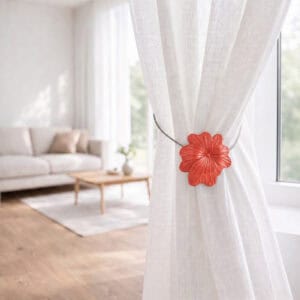 08 (living room lifestyle): Sheer white curtain held back by the terracotta flower tieback in a bright living room with a neutral sofa and wood coffee table softly blurred behind.